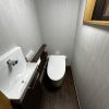 壁クロス・床材も張り替え、落ち着いた空間に生まれ変わったトイレ全景｜ストライプ柄のクロスと木目調クッションフロアで高級感ある仕上がり