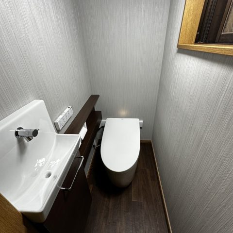 壁クロス・床材も張り替え、落ち着いた空間に生まれ変わったトイレ全景｜ストライプ柄のクロスと木目調クッションフロアで高級感ある仕上がり