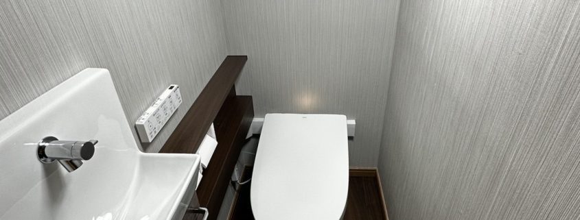 壁クロス・床材も張り替え、落ち着いた空間に生まれ変わったトイレ全景｜ストライプ柄のクロスと木目調クッションフロアで高級感ある仕上がり
