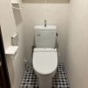 吊戸棚とベージュクロスでやや圧迫感のあるトイレ空間｜東京都大田区のトイレリフォーム施工前の様子」
