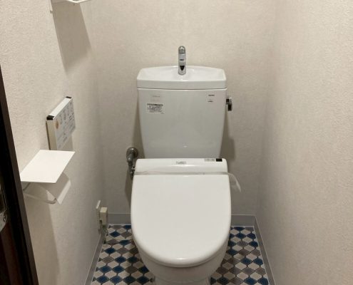 吊戸棚とベージュクロスでやや圧迫感のあるトイレ空間｜東京都大田区のトイレリフォーム施工前の様子」