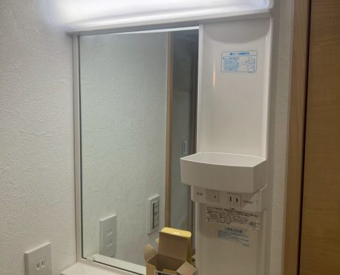 東京都大田区の賃貸マンション原状回復工事で交換した新しい洗面化粧台。LED照明付きミラーと白いクロスで明るく清潔感のある仕上がり