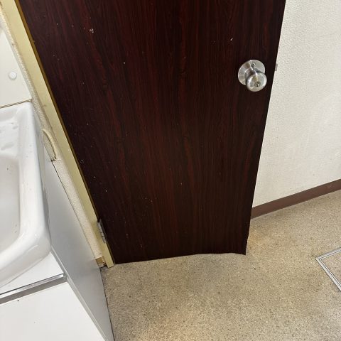 東京都大田区の賃貸マンションで施工前の古いトイレ扉と劣化した床の様子