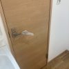 東京都大田区の賃貸マンションで原状回復工事後に交換された明るい木目調のトイレ扉