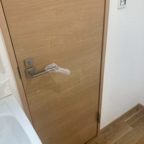 東京都大田区の賃貸マンションで原状回復工事後に交換された明るい木目調のトイレ扉