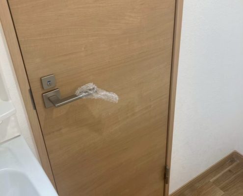 東京都大田区の賃貸マンションで原状回復工事後に交換された明るい木目調のトイレ扉
