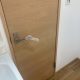 東京都大田区の賃貸マンションで原状回復工事後に交換された明るい木目調のトイレ扉