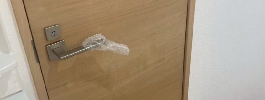 東京都大田区の賃貸マンションで原状回復工事後に交換された明るい木目調のトイレ扉