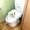 東京都大田区の賃貸マンションで原状回復工事により交換された最新型ウォシュレット付きトイレ。木目調の床とホワイト×グリーンのクロスで清潔感と快適性が向上した施工後の様子