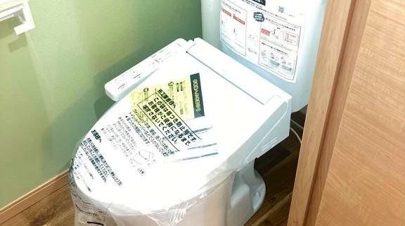 東京都大田区の賃貸マンションで原状回復工事により交換された最新型ウォシュレット付きトイレ。木目調の床とホワイト×グリーンのクロスで清潔感と快適性が向上した施工後の様子