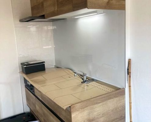 東京都大田区の賃貸マンションで施工したシステムキッチンリフォーム後の様子。クリナップ『ラクエラ』シリーズを採用し、木目調の扉とホワイトパネルで明るく温かみのある空間に生まれ変わった状態。
