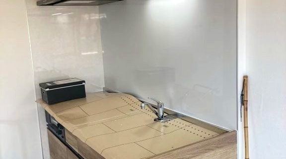 東京都大田区の賃貸マンションで施工したシステムキッチンリフォーム後の様子。クリナップ『ラクエラ』シリーズを採用し、木目調の扉とホワイトパネルで明るく温かみのある空間に生まれ変わった状態。