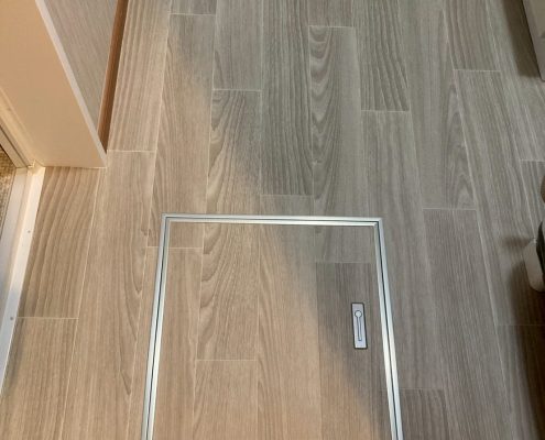 サンゲツHM-17077を使用した洗面室床の張り替え後。木目調のグレーベージュカラーが温かみと上品さを演出し、点検口を新設してメンテナンス性も向上。