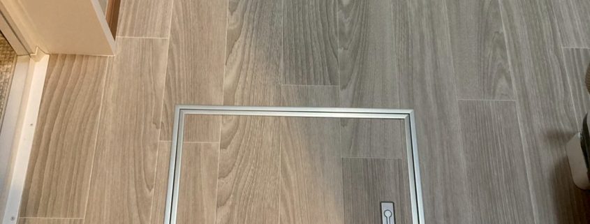 サンゲツHM-17077を使用した洗面室床の張り替え後。木目調のグレーベージュカラーが温かみと上品さを演出し、点検口を新設してメンテナンス性も向上。