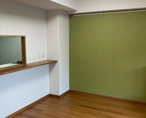 アクセントクロスとヘリンボーン調フローリングを採用したキッチン内装リフォーム施工後の様子。落ち着きと温かみのある空間に仕上がったマンションのキッチン。