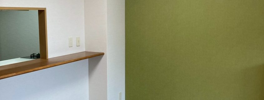 アクセントクロスとヘリンボーン調フローリングを採用したキッチン内装リフォーム施工後の様子。落ち着きと温かみのある空間に仕上がったマンションのキッチン。