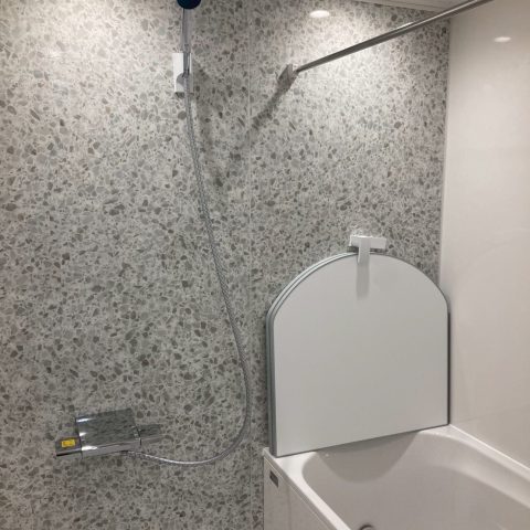 マンション浴室リフォーム後のユニットバス内部。明るい石目調パネルと使いやすいシャワー位置の施工例