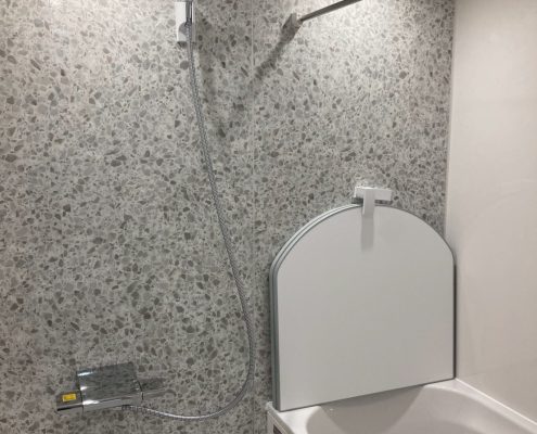 マンション浴室リフォーム後のユニットバス内部。明るい石目調パネルと使いやすいシャワー位置の施工例